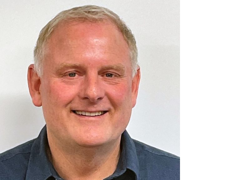 Smiling middle-aged man in blue shirt against white background