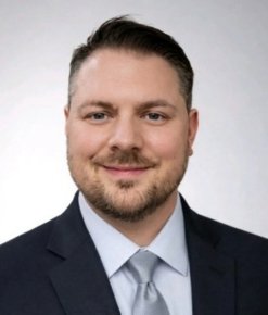 Professional headshot of smiling man in suit and tie